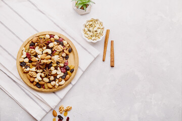 Aesthetic wooden bowl with mixed nuts from above. Healthy food and snacks. Walnut, almonds, hazelnuts and cashews. Raisins and cranberries