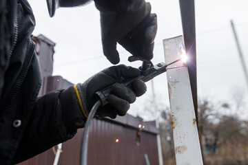 Welder man welding metal iron with electrodes, worker wearing protective helmet and gloves. Close up of electrode welding and electric sparks. Shielded metal arc welding