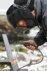 Shielded metal arc welding. Worker welding metal with electrodes, wearing protective helmet and...