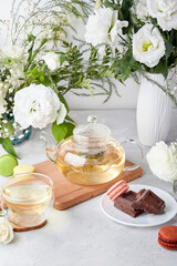 Fototapeta na wymiar Morning table setting. Green tea, macaroon desserts, chocolate, white flowers - time for yourself, enjoy your time concept