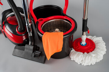 Cleaning concept mop and bucket, vacuum cleaner. Cleaning products and spin mop with red details on...