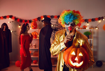 Man dressed up as evil clown holding jack o lantern and doing Shhh Tss Don't speak Keep silent...