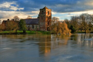 Naklejka na ściany i meble Tranquil view of the Church at Atcham, Shropshire, England, reflected in the River Severn