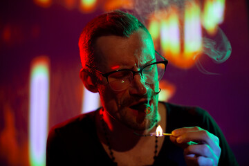 Man lighting cigar with match on night street