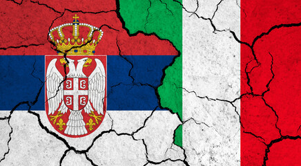 Flags of Serbia and Italy on cracked surface - politics, relationship concept
