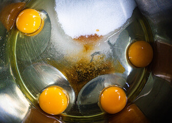 Eggs sugar and vanilla cake ingredients in a metal bowl