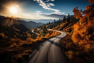 Fototapeta premium meandering road in the mountains through autumn forest, sunset. 