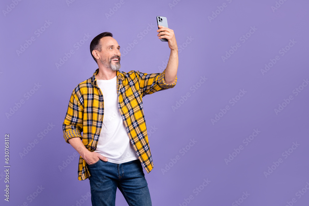 Poster Photo of positive man with white gray beard wear yellow plaid shirt making selfie on smartphone isolated on purple color background