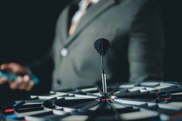 Businessman showing business investment target using virtual darts to target board on black background, business and investment concept
