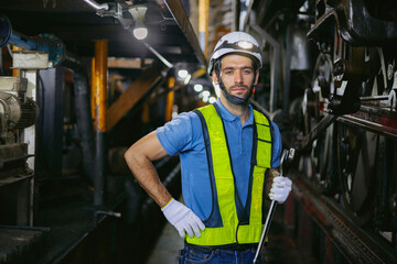 Industrial worker holding a wrench to maintain machinery and looking at camera