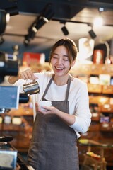 Cheerful woman making a coffee cup in cafe,Barista holding a cup of hot coffee for the first Morning.