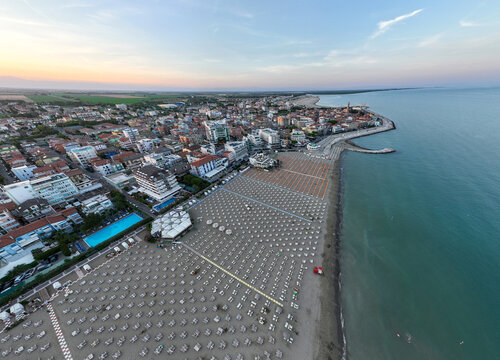 Drone photograph of the coastline of Caorle, Venice, Italy at sunset time. Umbrellas in the County Resort town