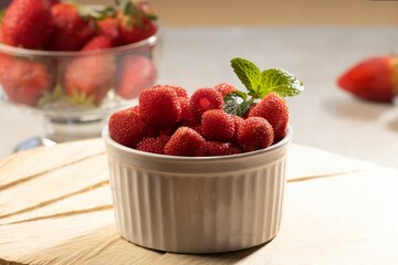 A wooden board with a bowl of delicious red raspberries