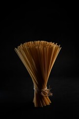 Close-up view of raw noodles tied up with a rope on a black surface