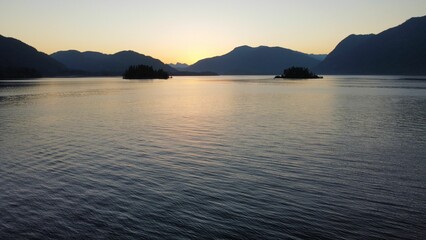 the sun sets over the mountains in the water and the water is calm