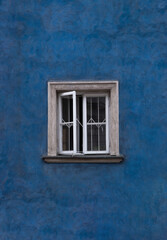 Opened window frame in old town house with blue walls