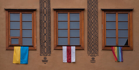 Ukrainian flag, belarusian flag and rainbow flag  hanging from the window of old town house