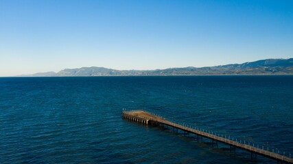Fototapeta na wymiar Scenic view of a tranquil pier in front of majestic mountains and a crystal blue sky