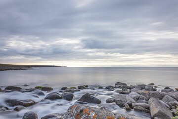 River meandering through a riverbed filled with rocks surrounded by a cloudy sky in Iceland