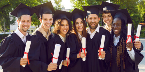 Happy diverse graduates in college campus yard. Group portrait of seven joyful mixed race...