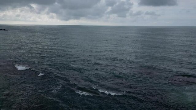 Aerial Of A Person Standing On The Edge Of A Cliff And Looking At The Calm Sea