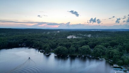 Aerial view of a landscape of a lake and green trees at sunset