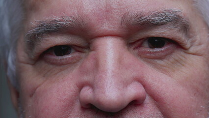 Intense macro close-up of a senior man with wrinkles staring at camera with serious stern expression displaying old age and experience