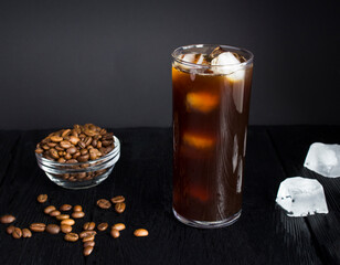 Cold brew coffee with ice in a tall glass on the dark background. Close-up.