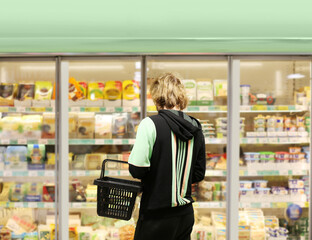  Man choosing frozen food from a supermarket freezer., reading product information