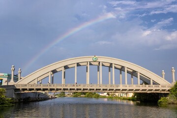 Vibrant rainbow in the cloudy sky over a bridge and the San Juan river. Matanzas, Cuba.