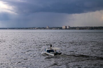 Stormy cloudscape over the town and sea with a floating fishing boat. Matanzas, Cuba.
