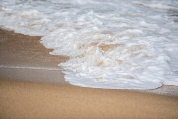 Soft ocean waves with foam on a sandy beach