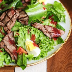 Closeup of a salad with lettuce leaves with beef and egg
