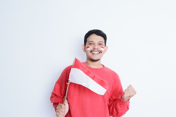 Indonesian man clenched fist, carrying red and white flag, showing excitement when celebrating independence day