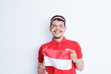 Indonesian man clenched fist, carrying red and white flag, showing excitement when celebrating independence day