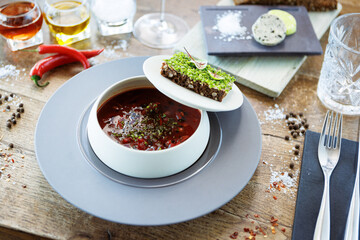 Borscht soup. Black Angus beef, beetroot, sour cream, toasted bread with smalec in a bowl. Delicious healthy food closeup served for lunch on a table in modern gourmet cuisine restaurant