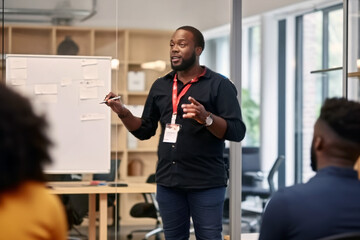 An engaging African American man delivers a dynamic corporate presentation. Captivating his audience, he shares insights within a professional boardroom setting