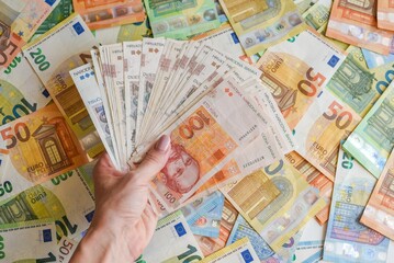 Person holds a stack of five hundred euro banknotes in his hands