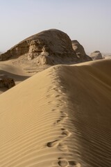 Scenic landscape of desert terrain featuring rugged hills of sand and large rocks on a sunny day