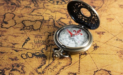 a small pocket watch resting on a piece of old world map