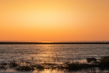 Fototapeta na wymiar Stunning sunset view of a vast body of water, illuminated in a beautiful orange hue