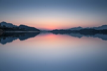 a lake with a mountain and a sunset in the background