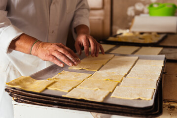 Unrecognizable chef standing at table and preparing pasta dough