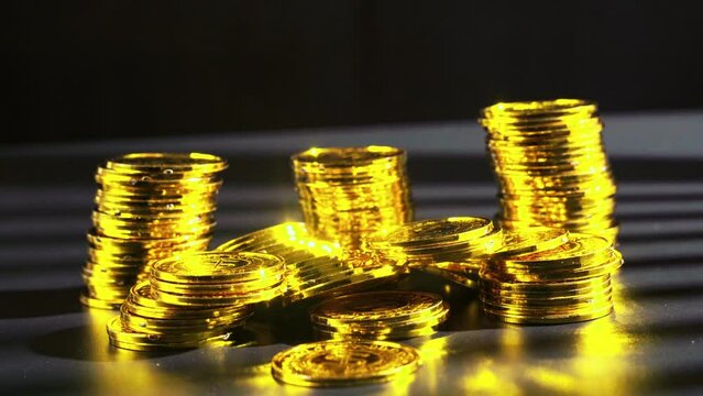 Closeup of shining golden coins on dark background - concept of wealth