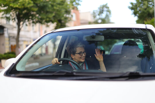 Senior businessperson drives a car on a busy road. They are distracted and reckless, risking an accident and their safety.