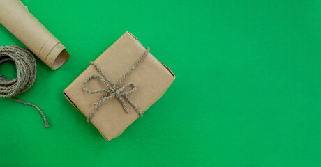 Christmas gift wrapping. Gift in craft paper, twine, paper on a green background.