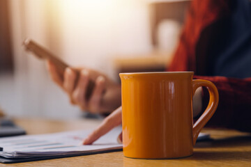 Cropped photo of Freelancer business Asian woman holding coffee cup and at doing planning analyzing the financial report, business plan investment, finance analysis the workplace.
