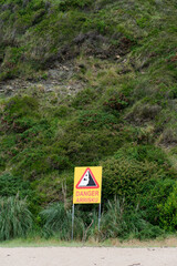 Panneau avertissant d'un danger au pied d'une falaise sur la plage d'Hendaye en français et en langue basque
