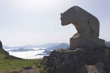 Bear statue dominating a landscape of mountains emerging from the clouds