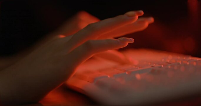 Female hand typing on keyboard, with red setup

